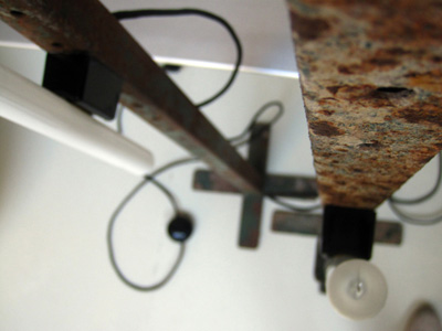 Dos lámparas hermanas gemelas, formades a base de perfil metálico tubular, que eran los pies de la estructura de unes caballerizas. La iluminación a base de linestras verticales